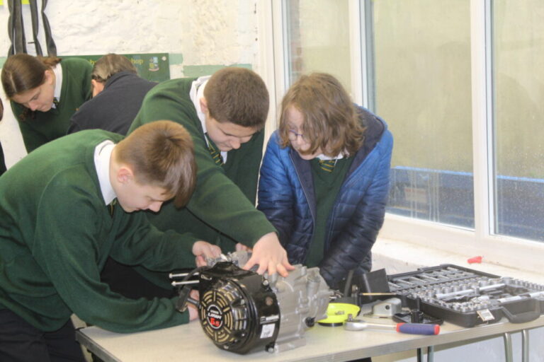 Three students looking at an engine